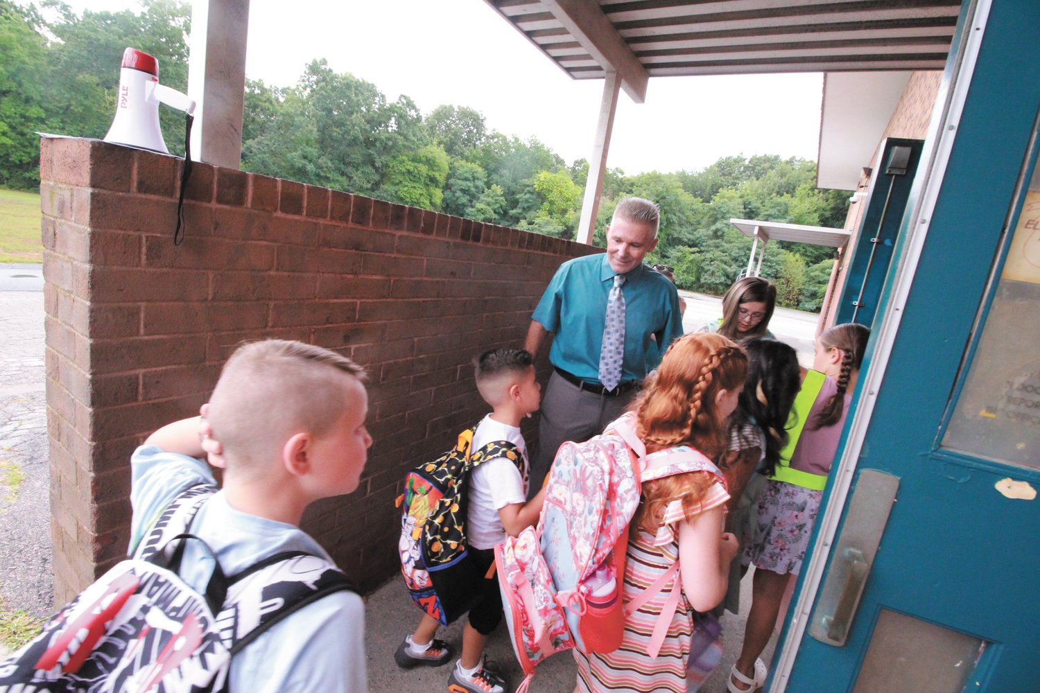 THERE TO GREET THEM: Hoxsie principal Gary McCoombs welcomes students back to school. The lifting of Covid restrictions enabled all the students with the exception of kindergartners to assemble in the all-purpose room.